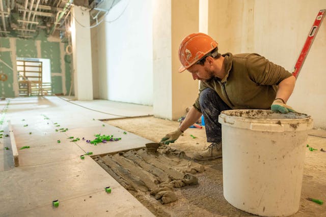 Profissional formado no curso de azulejista instalando pias de porcelanato em um projeto residencial moderno.